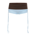 Blue bikini shorts with a brown gingham print waistband, featuring thin light blue side ties hanging down, shown against a plain white background.