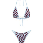 A two-piece bikini set featuring a burgundy and baby blue checkerboard pattern with baby blue trim, modelled at the beach.